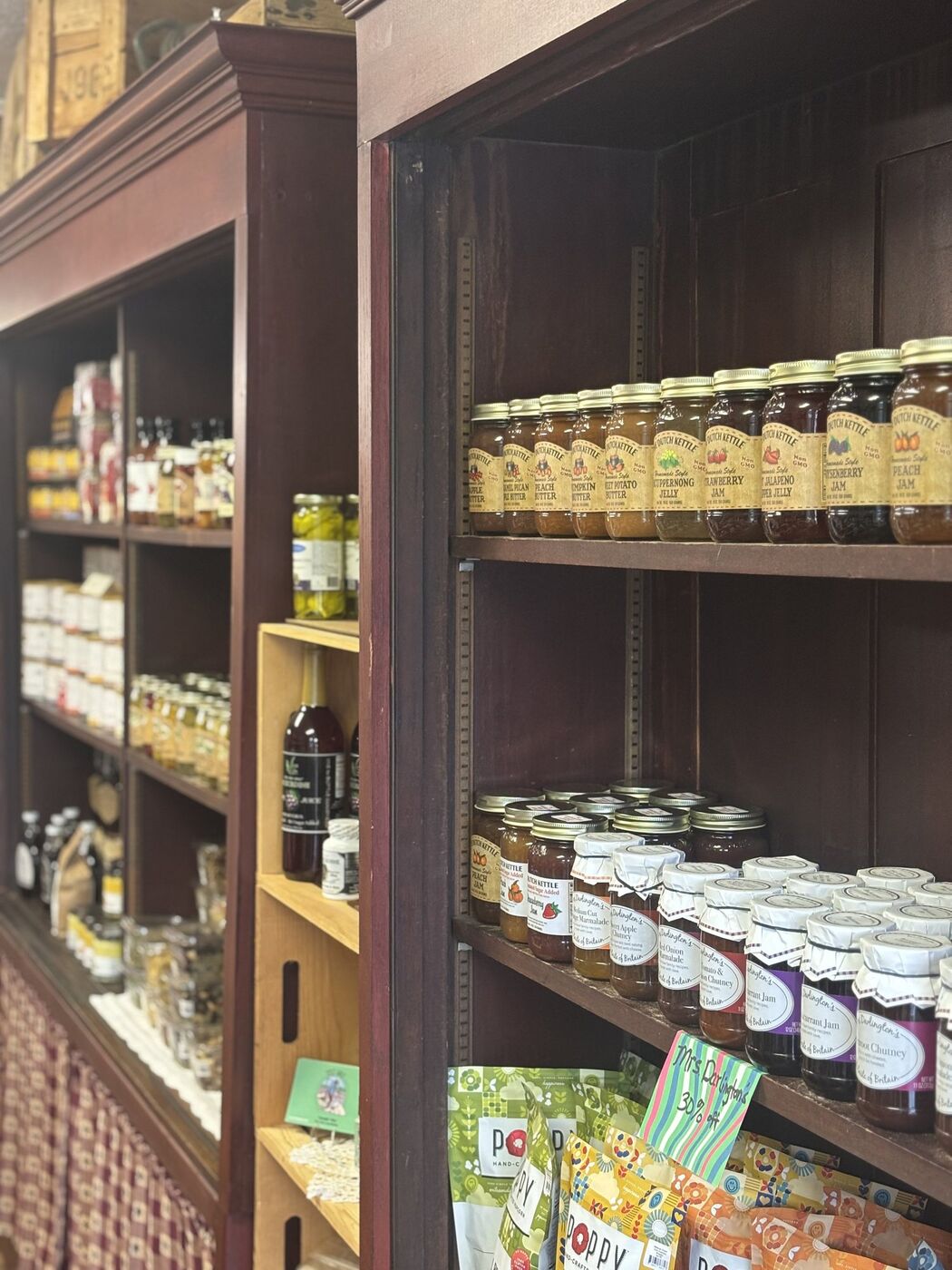 Wooden shelves lined with jars of jam, jelly, and fruit butter